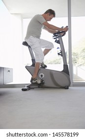 Side View Of Middle Aged Man On Exercise Bike Pedaling At Home