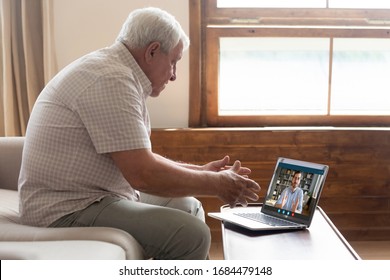 Side View Middle Aged Mature Older Man Sitting On Sofa, Looking At Computer Screen, Holding Video Call Listening Grown Up Handsome Son, Explaining How Important Stay At Home During Virus Outbreak.