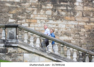 Side View Of Middle-aged Couple Climbing Steps Outside Old Building