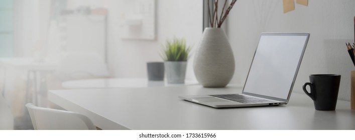 Side View Of Minimal Home Office Desk With Blank Screen Laptop, Decorations And Copy Space On White Desk  