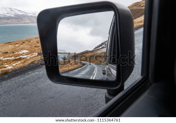 Side view\
mirror of a car, driving around in\
Iceland