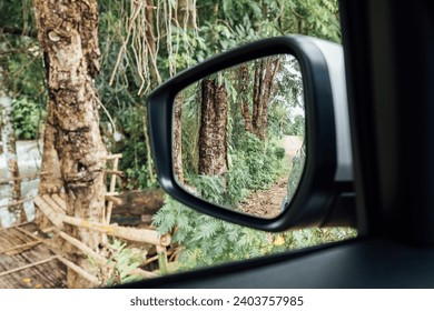 Side view mirror reflection on the road in forest