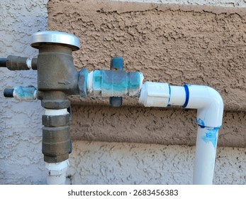 Side View of misaligned and broken junction of bronze alloy and plastic water pipe branching to drop irrigation system, close up