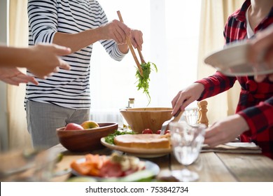 Side View Mi-section Of Group Of People Standing At Festive Dinner Table Serving Homemade Food To Plates During Holiday Celebration