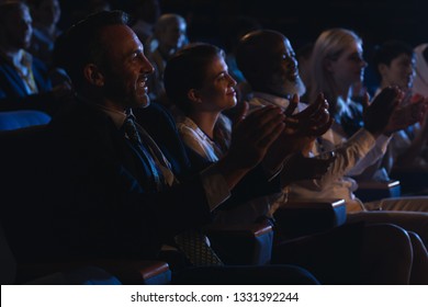 Side View Of Mixed Race Business Colleagues Sitting And Watching Presentation With Audience And Clapping Hands