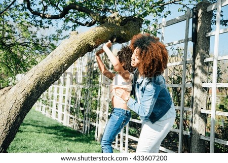 Side view of mother helping daughter to climb tree