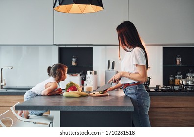 Side view of mother that with her little daughter preparing food indoors in kitchen. - Powered by Shutterstock