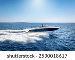 Side view of a motorboat cruising with high speed over the ocean and leaving a trail of bubbles and waves