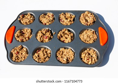 A Side View Of A Muffin Pan With Uncooked Bran Muffin Mixture Waiting To Go In The Oven On A White Background 