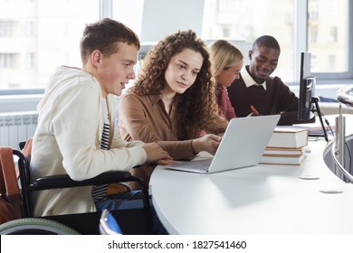 Side view at multi-ethnic group of students using laptop while studying in college, featuring boy using wheelchair - Shutterstock ID 1827541460