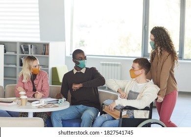 Side View At Multi-ethnic Group Of Students Wearing Masks While Studying In College Library With Young Man Using Wheelchair In Foreground, Copy Space