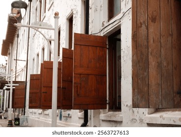 Side view of multiple open windows, aligned in a row, showcasing an architectural pattern and light play