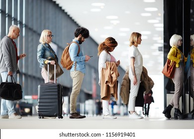 Side view of multiracial people standing in queue to check in in airport hall