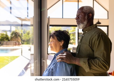 Side view of multiracial senior couple looking through window while standing in retirement home. Serious, unaltered, love, togetherness, support, assisted living and retirement concept. - Powered by Shutterstock