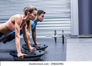 Side view of a muscular couple doing bosu ball exercises - Powered by Shutterstock