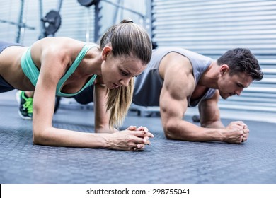 Side view of a muscular couple doing planking exercises - Powered by Shutterstock