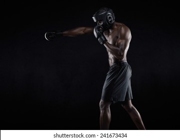 Side View Of Muscular Man Boxing On Black Background. Afro American Young Male Boxer Practicing Shadow Boxing.