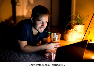 Side view of nice guy watching funny videos on internet, lying on soft blue carpet