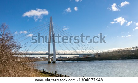 Side view of the Northern Spire Bridge in Sunderland taken from the River Wear's embankment on a sunny spring morning.  Showing blue sky and minimal white clouds.