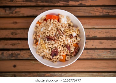 A side view of nut papaya granola cereal in a bowl with a spoon and yogurt on a wooden background and about healthy life