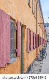 Side View of Nyboder Historic Naval Barracks, Row of Yellow Houses with Red Shutters, Bicycles Parked, Copenhagen