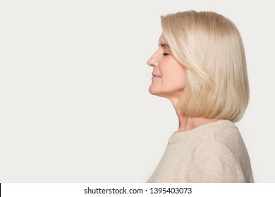 Side View Old Blond Woman Standing On Grey Background Aside Empty Copy Space For Advertisement Text, Senior Lady Profile Face Closed Eyes Enjoy Fresh Air Nice Fragrance Smell Aroma Or Dreaming Concept