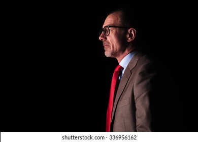 Side View Of An Old Business Man Looking Away From The Camera On Black Studio Background