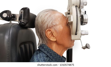 Side View Of Old Man Visiting Optometrist In The Hospital While Examining His Eyes By Using A Phoropter