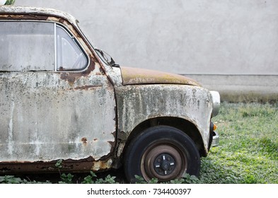 Side view of old rusty car parked on leaved place in grass.