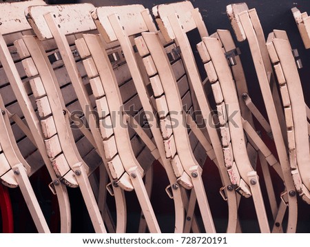 Side view old white painted folded wooden chair, stacked altogether in row pattern background, under warm evening sunlight