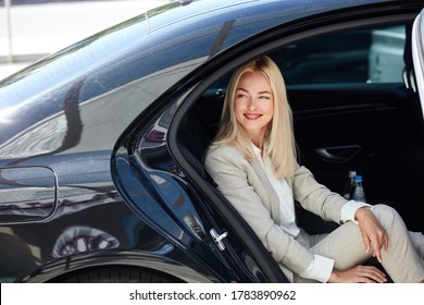 side view on attractive business lady sitting inside of luxurious car, waiting for personal private driver, business trip concept