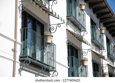Side view on balconies with wrought iron railings, on a Spanish style stucco building, in an architectural background