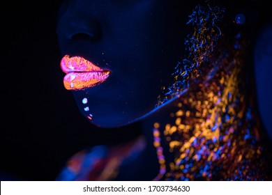 side view on beautiful young woman with fluorescent prints on face, unusual prints, body art. neon lights, uv ray, luminescence concept