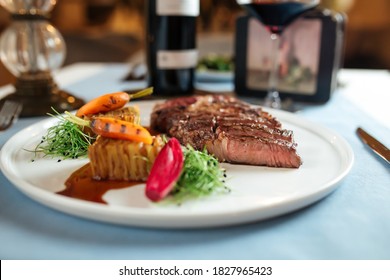 Side View On Cut Grilled Beef Ribeye Steak With Potatoes On White Plate