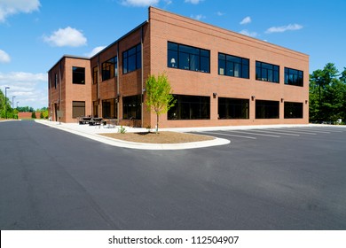 Side view on the generic red brick office building with parking lot - Powered by Shutterstock