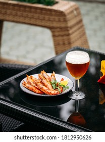 Side View On Golden Beer In A Glass With Langoustines On The Glass Table Outdoor