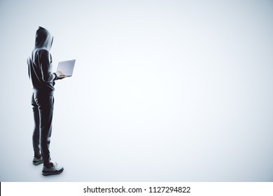 side view on hacker in grey sport suit with laptop at white background.
