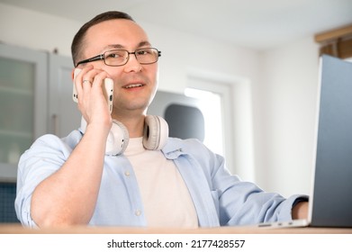 Side View On Happy Asian Man Talking On The Phone And Looking At Laptop Screen.Communication,work From Home