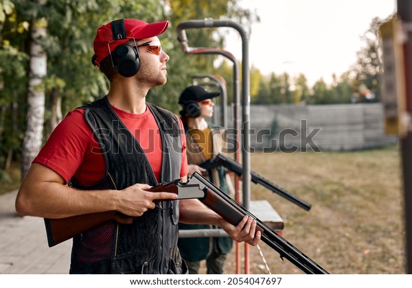 Side View On male Looking at side after shooting.\
Firearms for sports shooting, hobby.strong confident man in\
goggles, headset hold weapon. purpose and success. man ready to\
fire. hunter hobby.