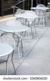 Side View On A Row Of Metal Patio Furniture With Sets Of Empty Tables And Chairs In The Courtyard Of A Public Park