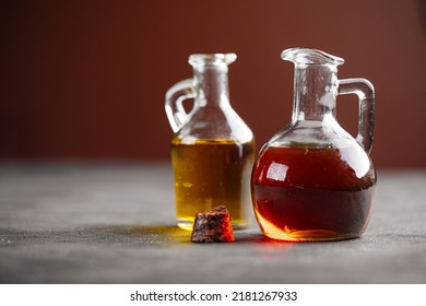 Side view on two lass jugs with oil for cooking on a grey background