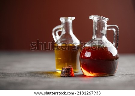Side view on two lass jugs with oil for cooking on a grey background