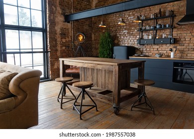 Side view on a wooden table and spacious industrial loft kitchen with vintage decor and black cabinets - Shutterstock ID 1987557038