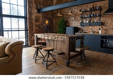 Side view on a wooden table and spacious industrial loft kitchen with vintage decor and black cabinets