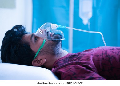 Side View On Young Man Breathing On Ventilator Oxygen Mask At Hospital Due Coronavirus Covid-19 Dyspnea Or Breathlessness - Concept Of Covid Infecting Millennial People