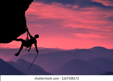 Side view on the young mountainer. Silhouette mountainer in action. The mountainer climbs to a hard route on the rock to reach its goal and success. Landscape of mountains and sunset in the background
