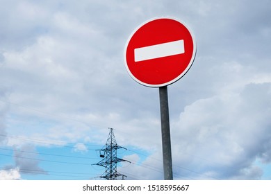 Side view onto international traffic sign 'No Entry' or 'No Entrance'. Blurred power line tower is on cloudy background