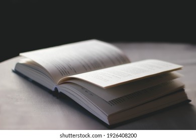Side view of open book lies on table with white tablecloth on black background  