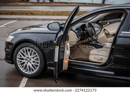 Side view of the open driver's door, mirror, dashboard of the car. Left front door. A new modern shiny parked black car. Interior luxury car with tinted glass standing at parking. Modern car exterior.