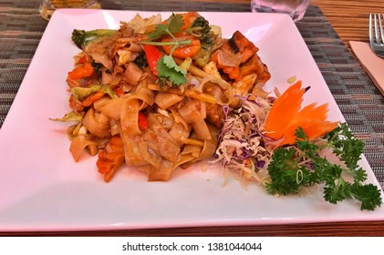 A Side View Of Pad Thai Noodles Served On Square Shaped Ceramic Plate